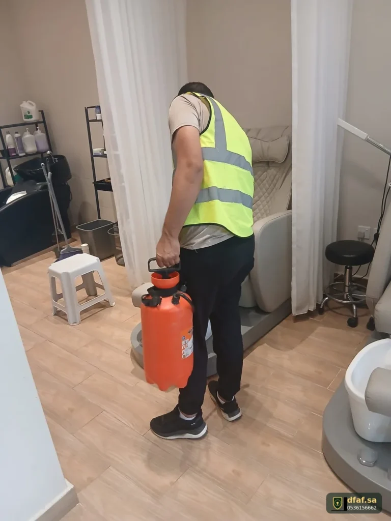 فني ضفاف الماسية يحمل ضاغط رشّ المبيد لمعالجة النمل الأسود داخل صالون تجميل