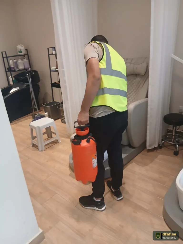 فني ضفاف الماسية يرشّ مبيد النمل الأسود بين مقصورات صالون تجميل